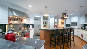 Una cocina moderna con electrodomésticos de acero inoxidable, una isla central con taburetes de bar e iluminación colgante.