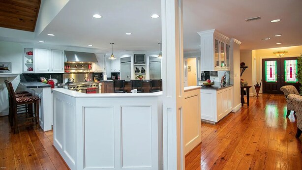 Una cocina amplia con armarios blancos, una isla central y techo de madera.