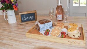 A breakfast tray with pastries, strawberries, and a bottle of wine on a wooden table. - Ysgubor Blaenparc Barn - UK41030 (Dihewyd<br />, near Aberaeron)