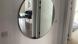 A round mirror on a wall with a view into a living room. - Luxury 2-Bed High-rise Apartment with beautiful view near Excel, &O2. Next to CR (London)