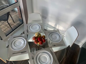 Une table à manger avec quatre chaises, un panier de fruits et un verre d’eau.