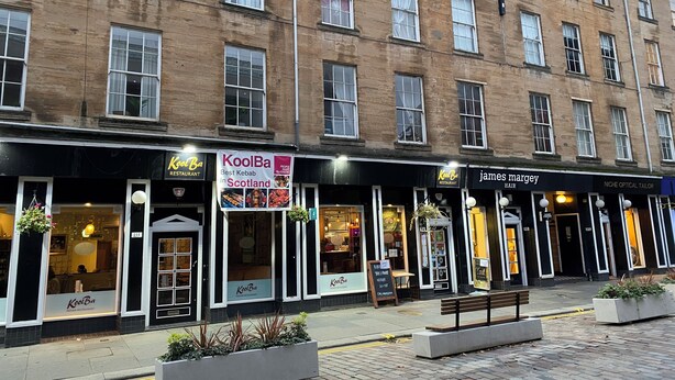 A row of commercial buildings with storefronts, including a restaurant named KoolBa and a hair salon named james margey. - Lovely 1-bed Apartment in Glasgow Merchant City (Glasgow)