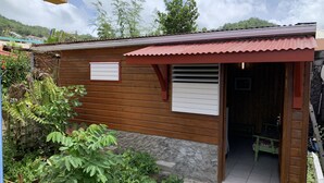 A small wooden building with a red roof, a wooden door, and a small window. - Studio 40 m2 (les trois ilets, le marin)
