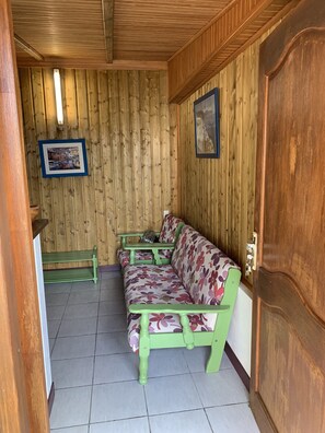 Une pièce aux murs lambrés, avec un canapé vert et un banc.