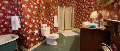 A bathroom with a bathtub, toilet, shower, and vanity with a mirror.
