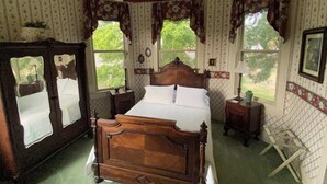 Ein Schlafzimmer mit einem hölzernen Bett, zwei Nachttischen, einem Deckenventilator und einem Fenster mit Vorhängen.