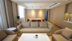A modern living room with a sofa, a coffee table, and a dining area with a table and chairs.