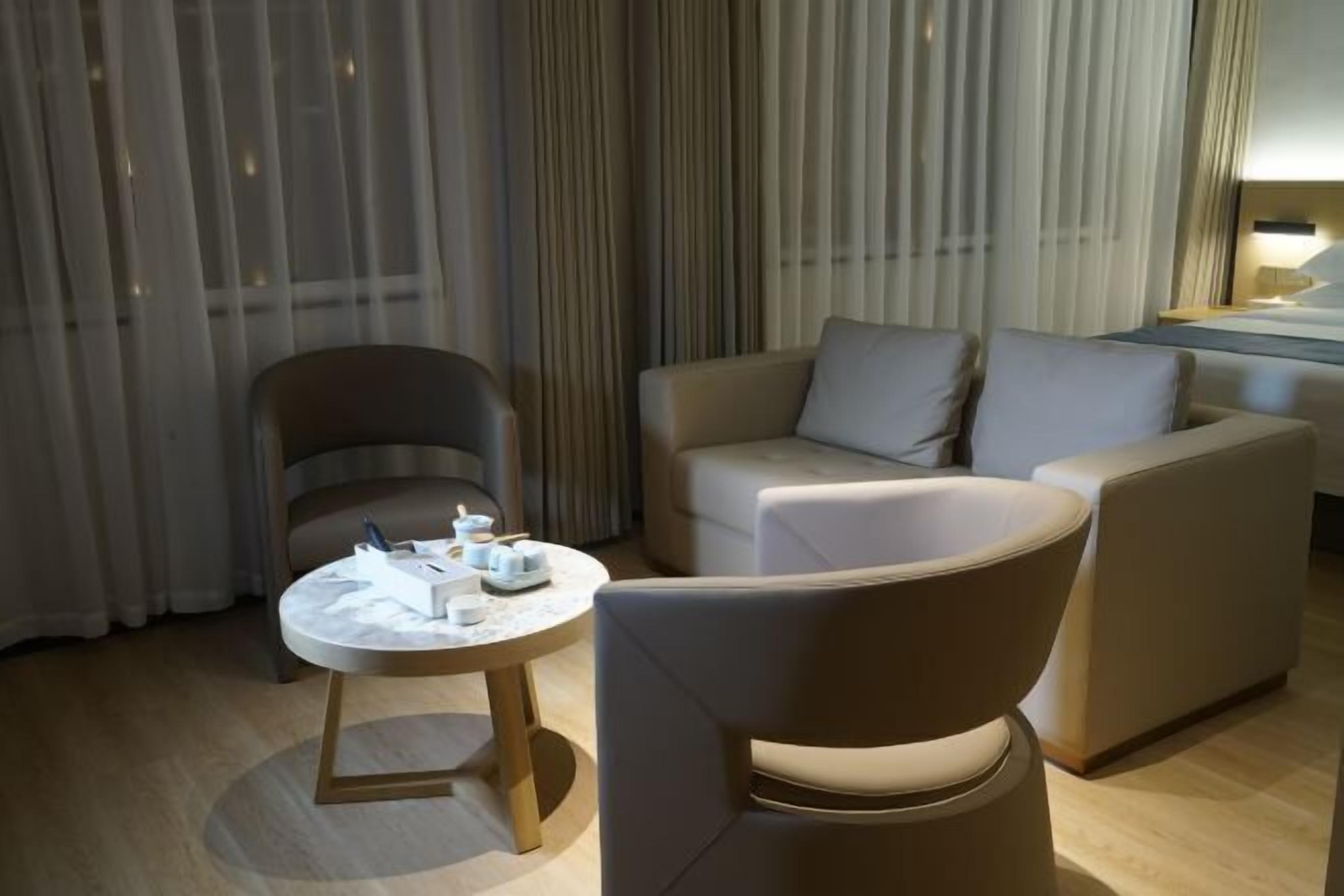 Une chambre d’hôtel moderne avec une table ronde, un canapé et un fauteuil.