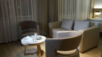 Une chambre d’hôtel moderne avec une table ronde, un canapé et un fauteuil.