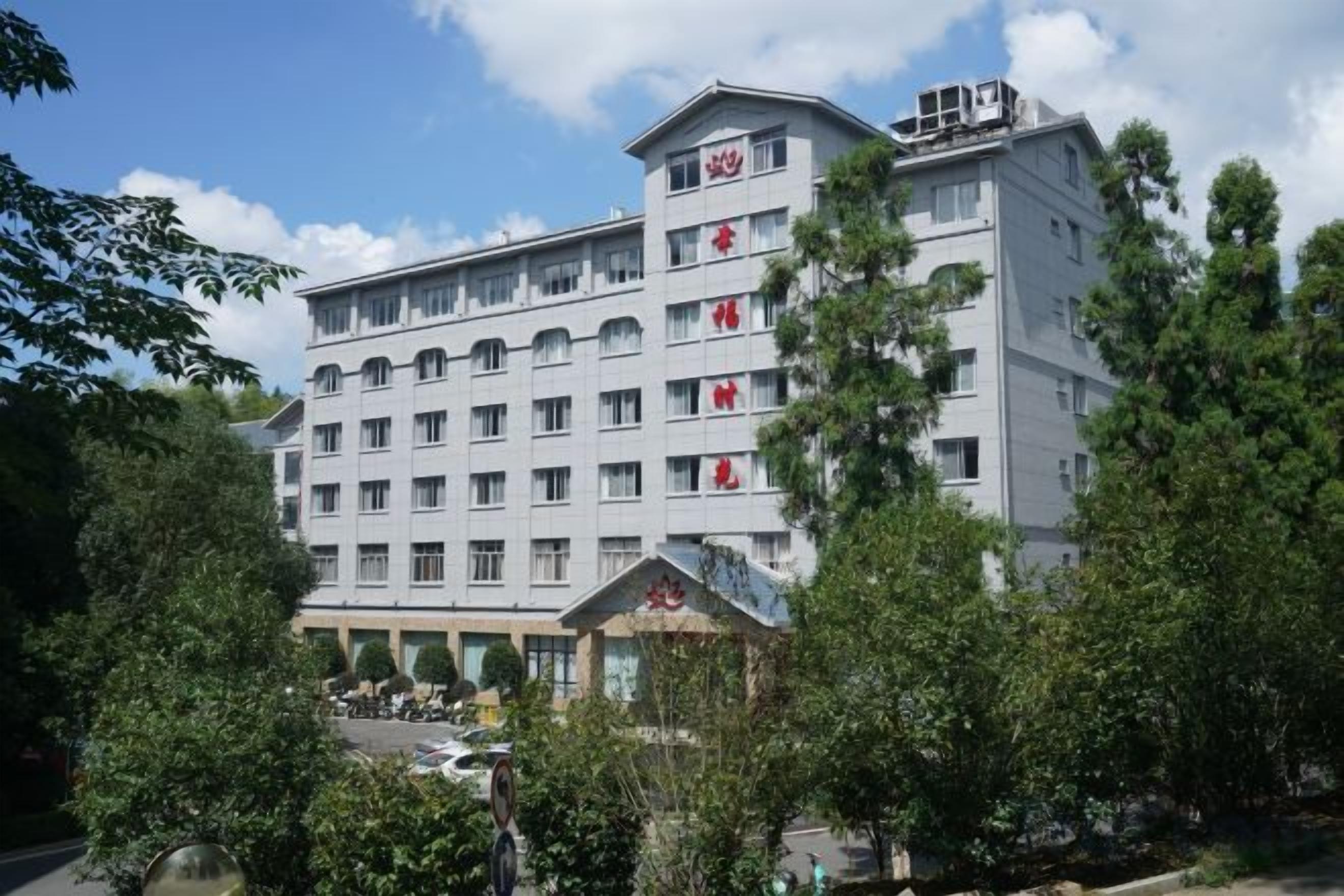 Un hotel de varios pisos con fachada plana, numerosas ventanas y una terraza en la azotea.