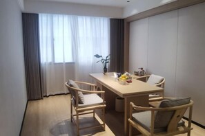 A hotel room with a wooden dining table, four chairs, a vase with flowers, and a large window with curtains. - Lotus Hotel (Jianning)