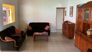 Un saló amb un sofà marró fosc, un armari a joc, una taula de centre de fusta i un moble de fusta amb portes de vidre.