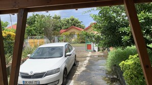 Un cotxe blanc estacionat a la calçada, amb una casa al fons.