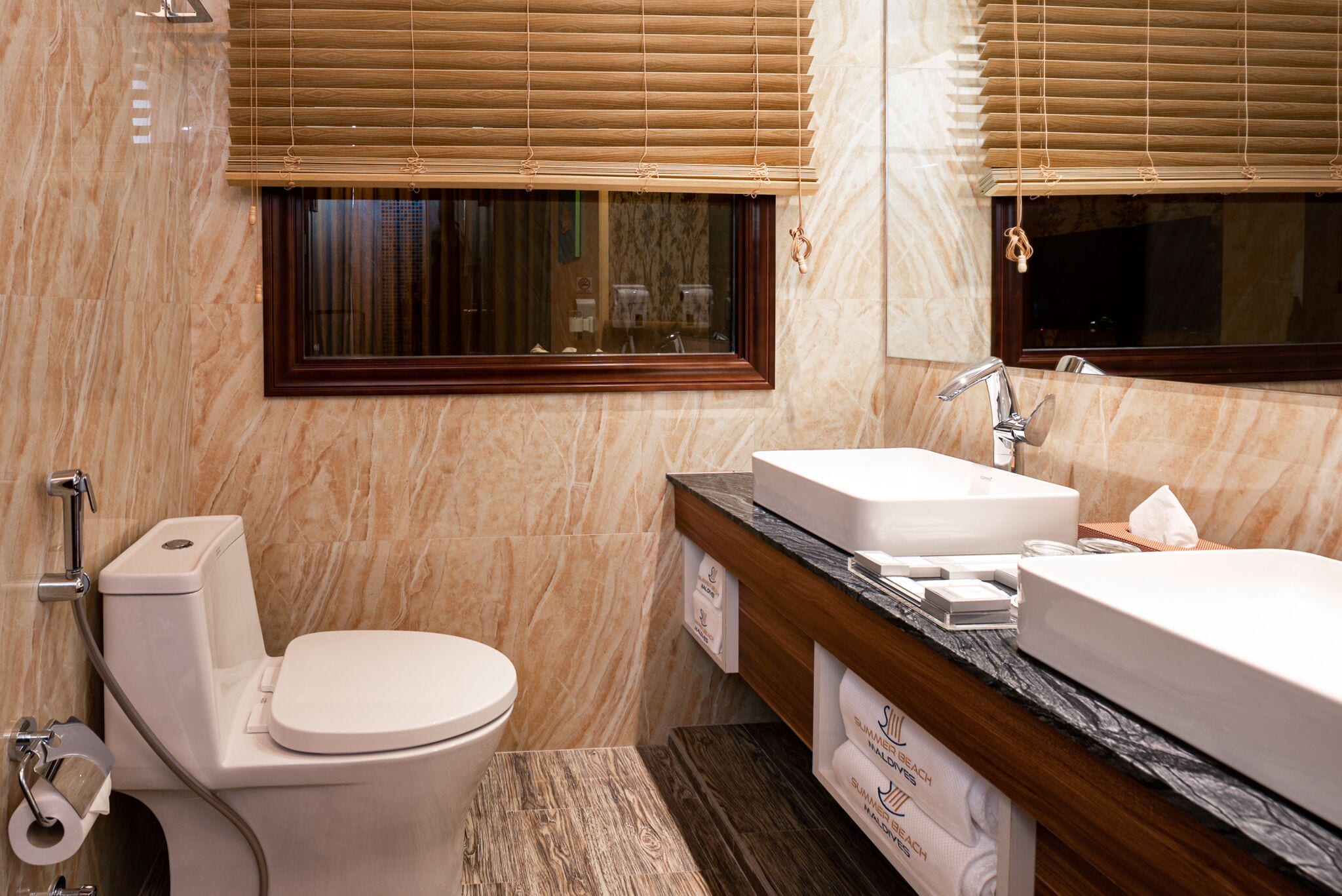 Un baño con inodoro, lavamanos y ventana con persianas.