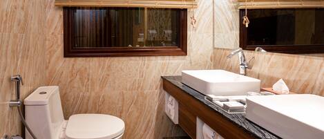 Une salle de bain avec des toilettes, un lavabo et une fenêtre avec des stores.