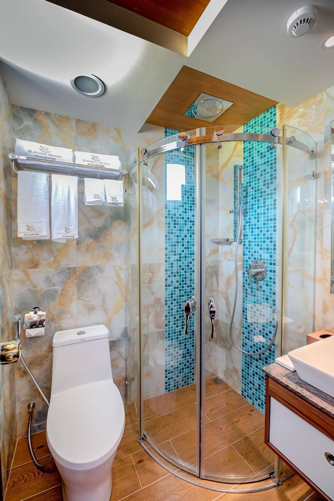 A bathroom with a glass-enclosed shower, a toilet, and a vanity with a sink.