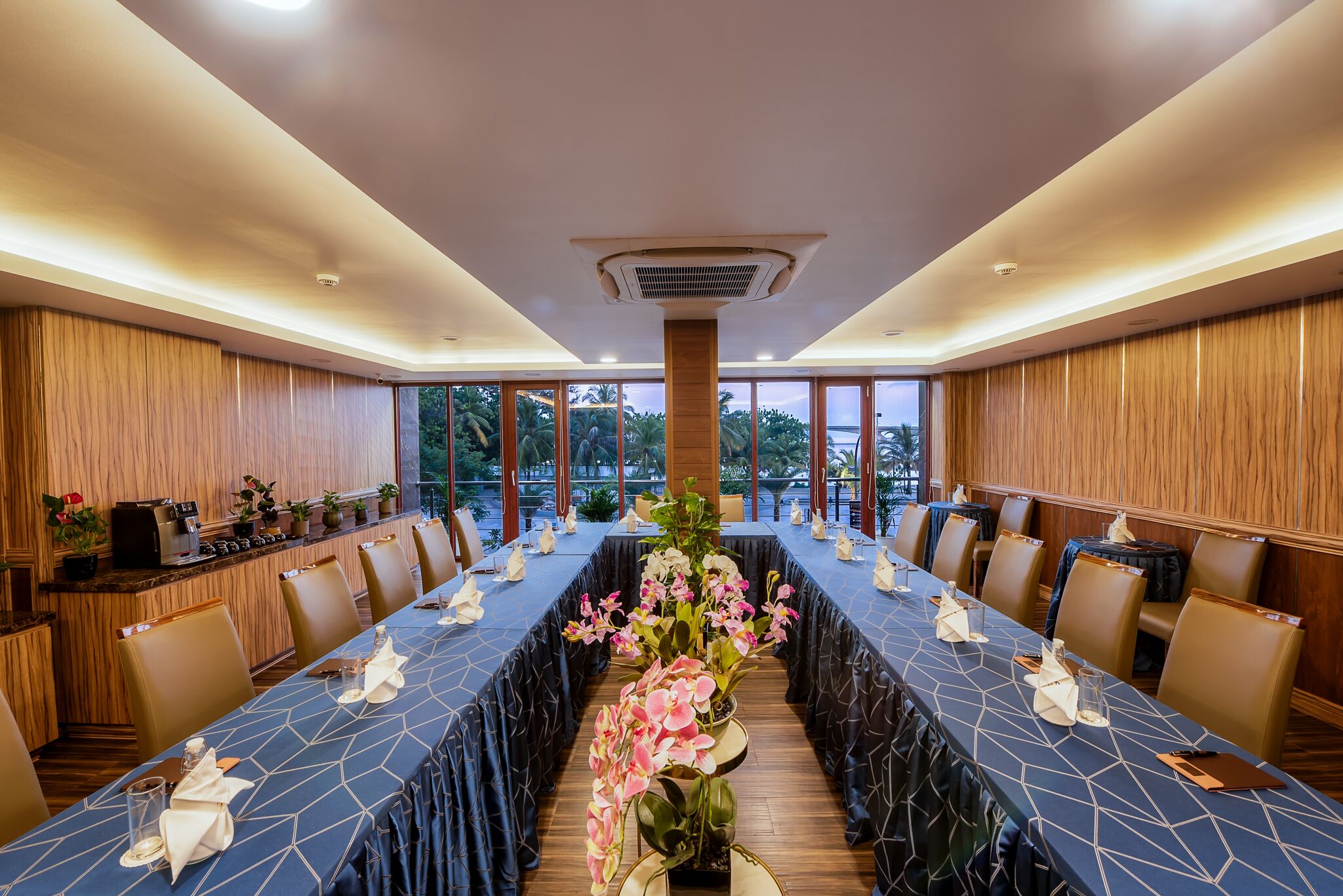 A conference room with a long table, chairs, and a central floral arrangement.