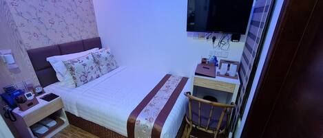 A neatly arranged bedroom with a bed, bedside table, TV, and a small wooden chair.