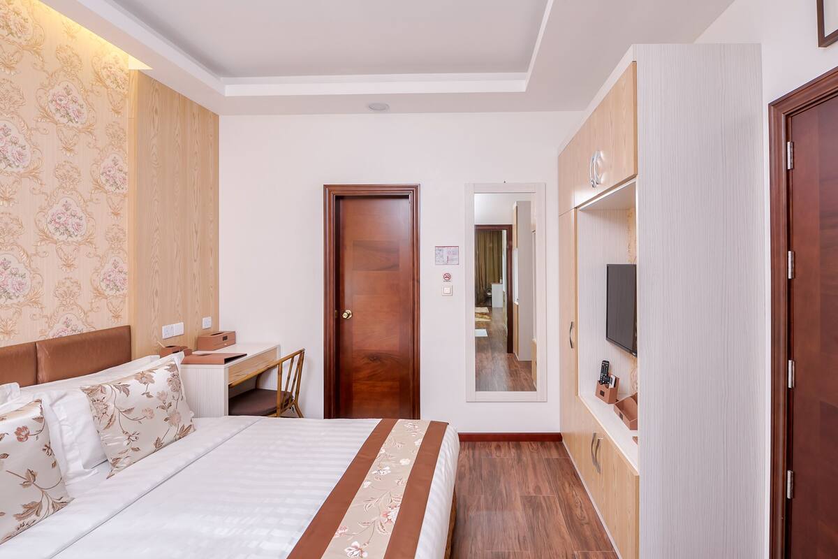 A hotel room with a bed, a desk, a television, and a wardrobe.