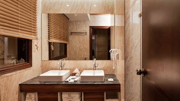 Un baño con dos lavamanos, un espejo grande, persianas de madera y una pared de mármol.