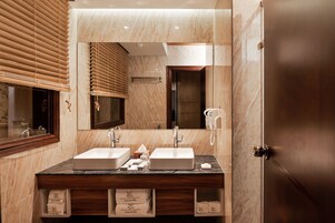 Un baño con dos lavamanos, un espejo grande, persianas de madera y una pared de mármol.