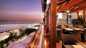 A restaurant with outdoor seating overlooking a beach and a bridge. - Summer Beach Maldives (Malé)