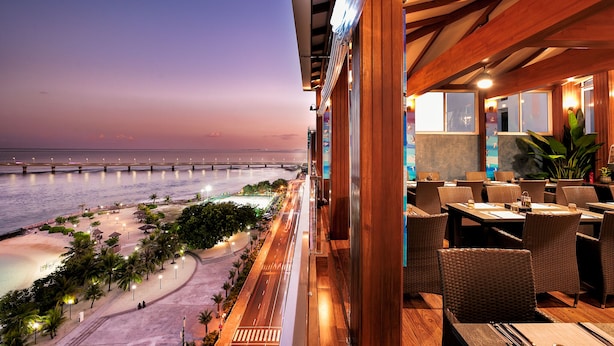 A restaurant with outdoor seating overlooking a beach and a bridge. - Summer Beach Maldives (Malé)