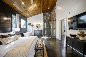 Une chambre moderne avec un grand lit, une coiffeuse, une douche et un téléviseur.