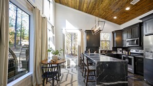 Een moderne keuken met een groot eiland, donkere kastjes en uitzicht op de omgeving.