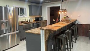 Una cocina moderna con electrodomésticos de acero inoxidable, una isla de madera y taburetes de bar.