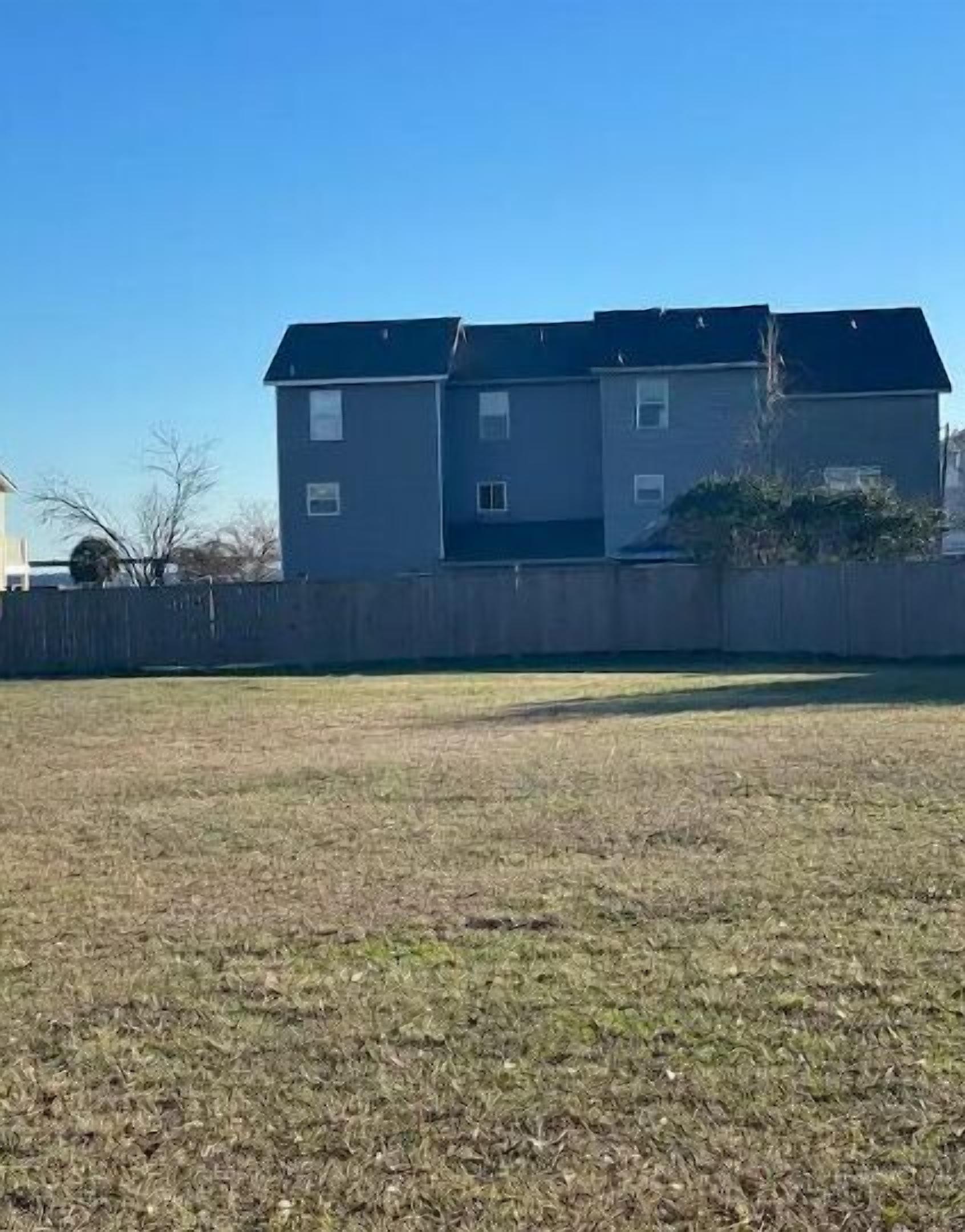 A two-story building with a flat roof and a fenced yard.
