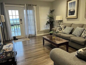 A living room with a sofa, coffee table, and a view of a balcony.