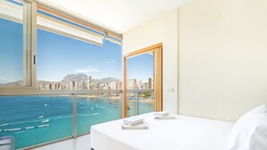 Hotelkamer met balkon met uitzicht op strand en stadsbeeld.