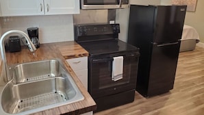 A kitchen with a stainless steel sink, a microwave, a stove, and a refrigerator. - Sanctuary, Lackland AFB, SeaWorld Fiesta Texas (San Antonio)