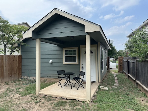 A small house with a porch, a table, and two chairs.