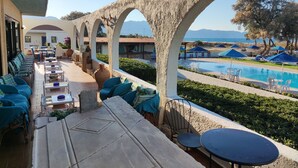 A poolside area with outdoor seating, a view of the sea, and a stone bridge. - Hotel Tsagarakis Beach (Malevizi)