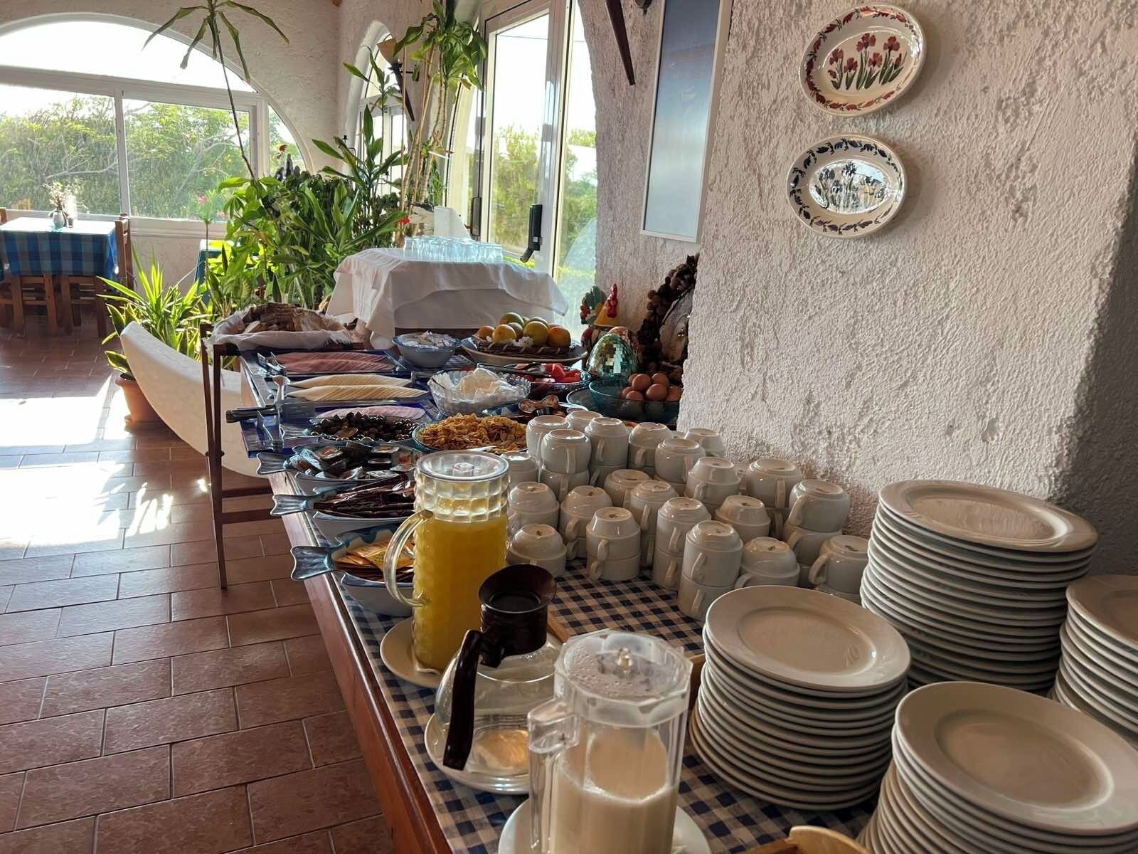 A buffet setup with various food items, plates, and a coffee station.