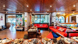 A spacious lobby with wooden ceiling, red sofas, and a variety of decorative items including pottery and plants. - Hotel Tsagarakis Beach (Malevizi)