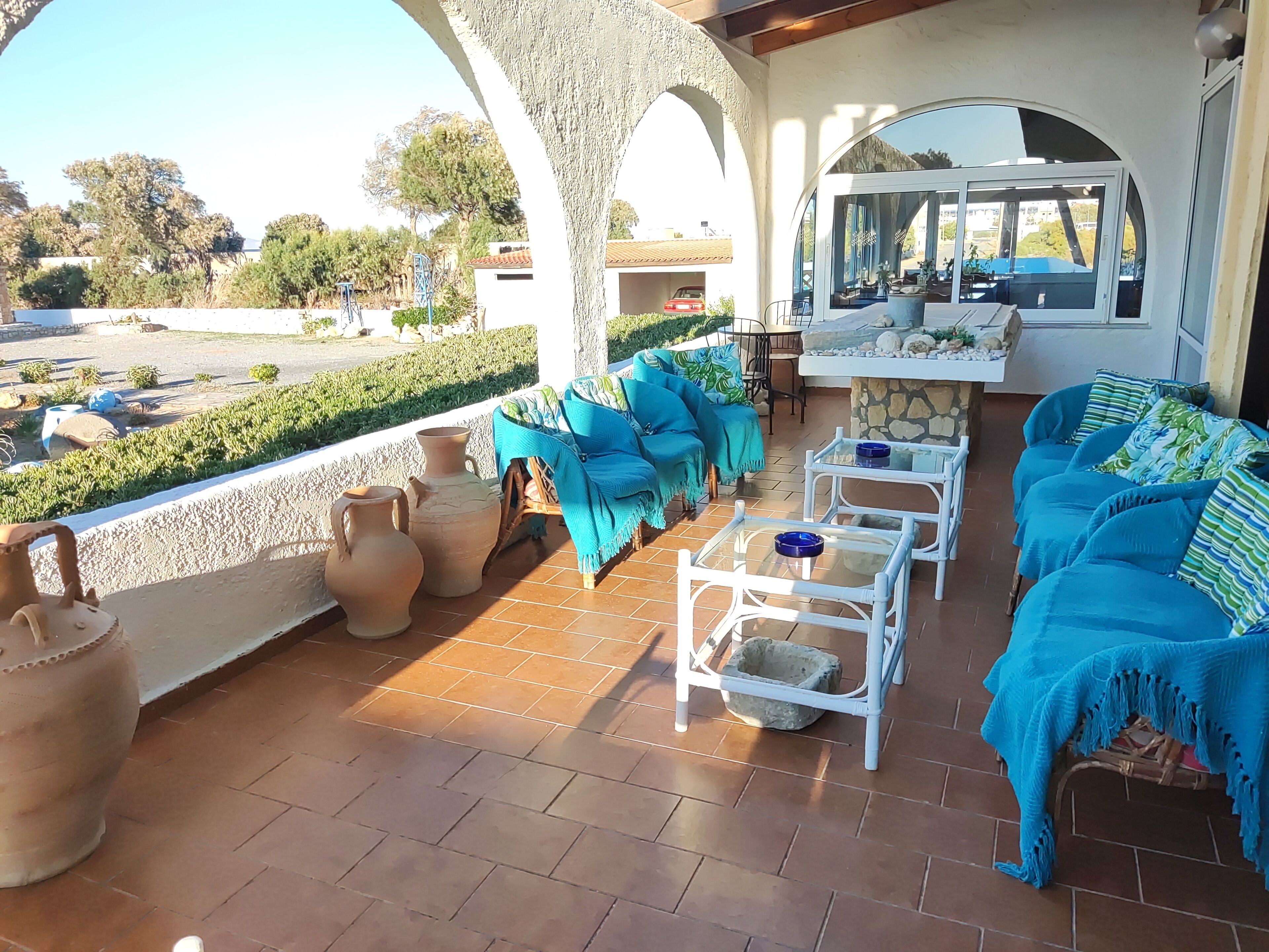 An outdoor patio with terracotta pots, blue upholstered seating, and a stone fireplace.
