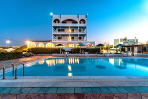 A swimming pool with a modern building in the background. - Hotel Tsagarakis Beach (Malevizi)