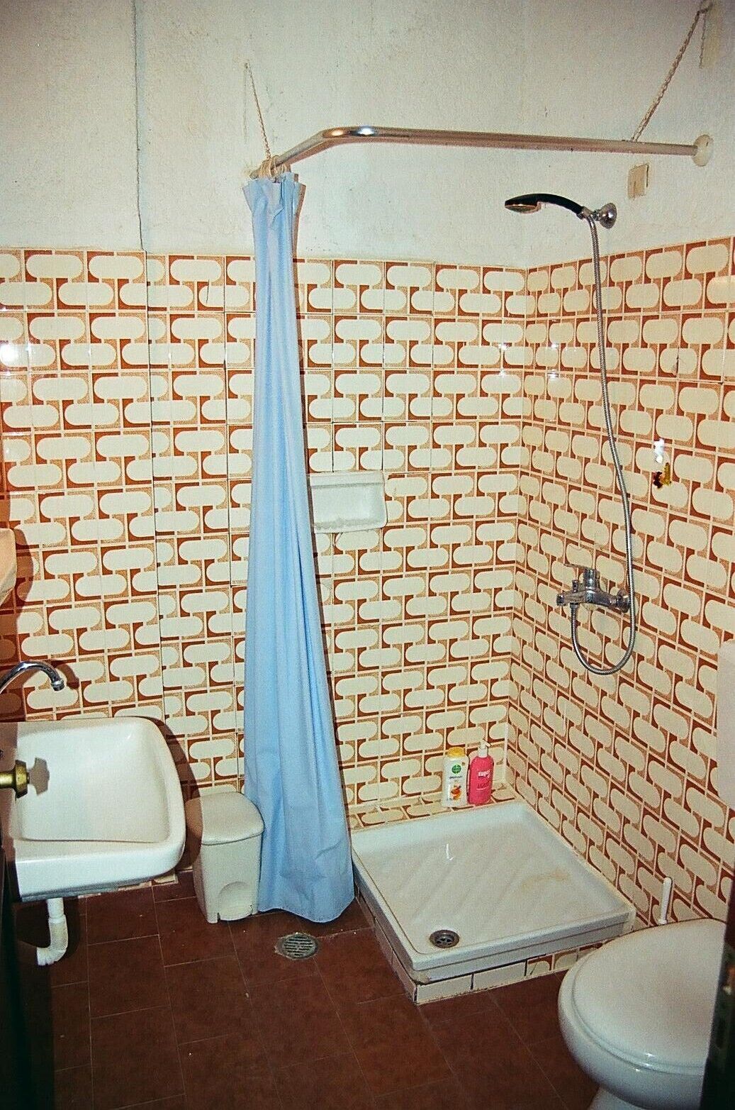 Une salle de bain avec un mur à motifs, une douche, des toilettes et un lavabo.