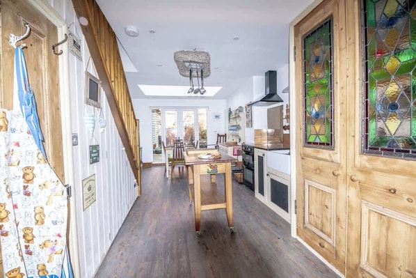 A kitchen with wooden flooring, a dining table, and a wooden door with stained glass.