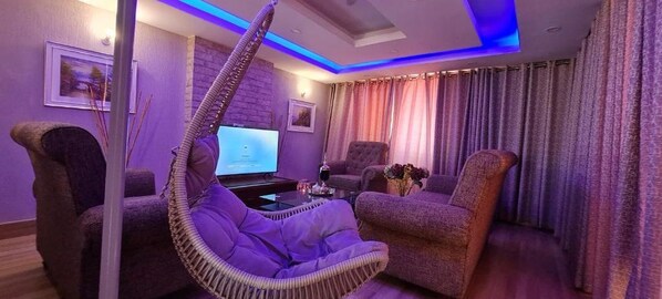 Ein modernes Wohnzimmer mit Hängekorbschaukel, Sofa und Fernseher.