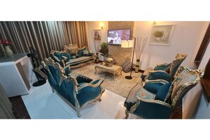 Ein Wohnzimmer mit aufwendigen Möbeln in Blau und Gold, einem Fernseher und dekorativen Gegenständen.