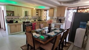 Una cocina moderna con armarios de madera, una isla central con asientos y un comedor.