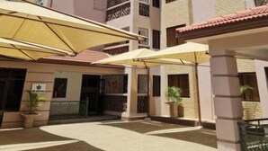 Un edificio de varios pisos con un patio central que incluye zonas de estar al aire libre y macetas con plantas.
