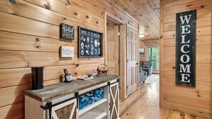 A wooden interior with a welcome sign, a wall-mounted sign listing animals of the woodlands, and a rustic counter with a phone and decorative items. - Spacious Cabin 15 min to Dollywood w/Hot Tub, Game Room, Valley Views (Sevierville)