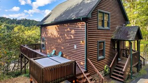 A log cabin with a deck, a small porch, and a window. - Spacious Cabin 15 min to Dollywood w/Hot Tub, Game Room, Valley Views (Sevierville)
