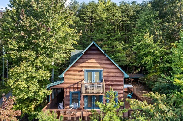 Eine Hütte mit einem Balkon, umgeben von dichtem Wald.