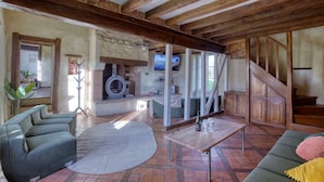 Un soggiorno rustico con travi a vista in legno, un camino in pietra e un muro in pietra.